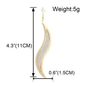 Dettaglio di lunghi orecchini a S dorati con dimensioni 11 cm di lunghezza e 1,5 cm di larghezza
