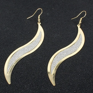 Dettaglio di orecchini dorati a forma di S con glitter argento e ganci a monachella