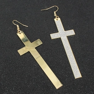 Dettaglio di orecchini a croce oro e argento con chiusura a gancio su fondo scuro