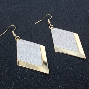 Dettaglio di orecchini a rombo con cornice in metallo dorato e finitura glitter argento
