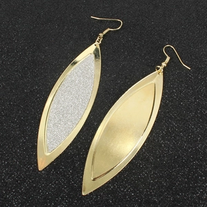 Dettaglio macro di orecchini a foglia geometrici con inserti glitter e finitura oro spazzolato