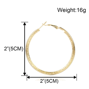 Dettaglio macro di orecchini a cerchio dorati da 5cm con finitura martellata e peso 16g