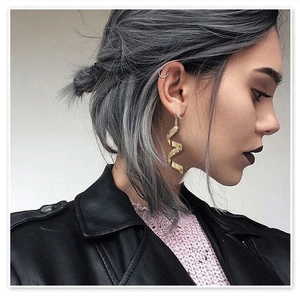 Orecchini a spirale dorati geometrici indossati da una modella in stile punk trendy