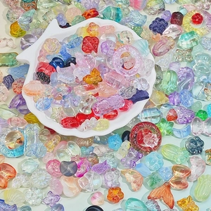 Colorful assorted glass pendants in various shapes like flowers and shells for DIY jewelry