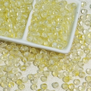 Gros plan de perles en verre jaune clair translucide avec surface lisse et trous percés
