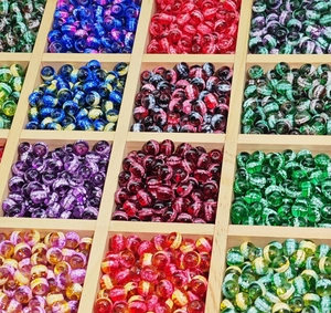 Detail of colorful handcrafted glass beads with crackle effect in a wooden grid box