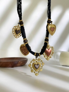 Dettaglio di cinque pendenti a cuore vintage su girocollo in pizzo nero con ombre morbide