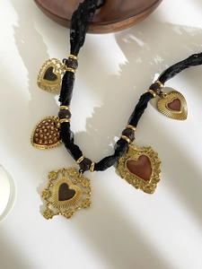 Dettaglio della collana vintage in pizzo nero con ciondoli a cuore e perle marroni