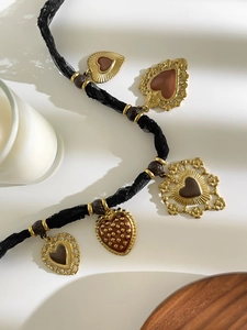 Dettaglio di ciondoli a cuore vintage su catena in pizzo nero con candela