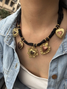 Dettaglio di ciondoli a cuore vintage su collana di pizzo nero con giacca jeans