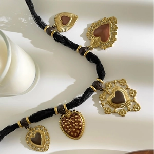 Collana retrò con pendenti a cuore, nastro di pizzo nero e perle su sfondo bianco