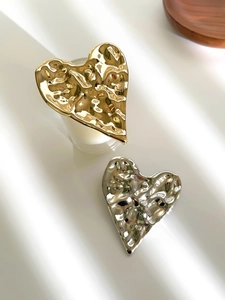 Detail of irregular crumpled heart brooches with gold and silver liquid metal texture
