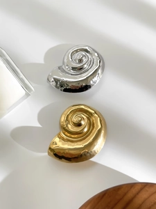 Macro shot of silver and gold irregular conch brooches with polished mirror finish