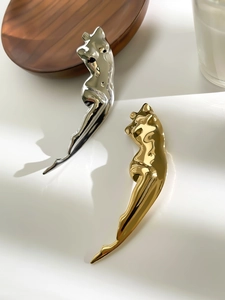 Artistic human body silhouette brooch in polished gold and silver finish on tray