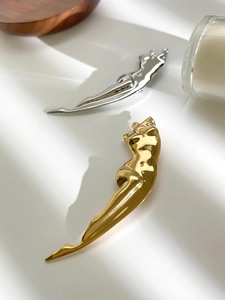 Artistic gold and silver female form brooches with polished finish on white fabric