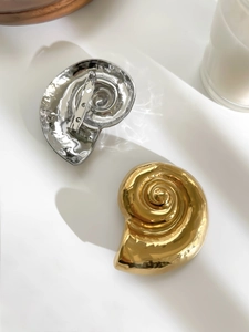 Detailed view of conch shell brooches in gold and silver with hammer texture and pin back