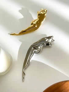 Detailed view of jaguar shaped brooches in polished gold and silver metallic finishes