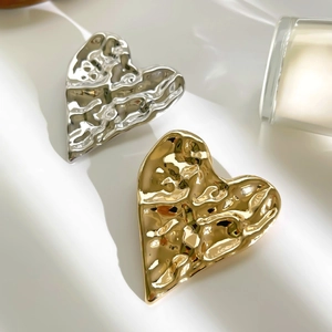Irregular vintage heart-shaped metal brooches in gold and silver with lava texture