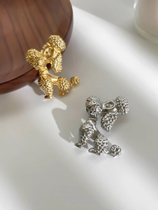 Detailed close-up of gold and silver poodle brooches with textured metal faux fur detail