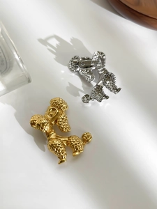 Detailed macro view of gold and silver poodle brooches with embossed fur texture