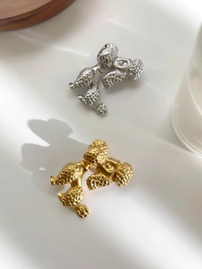 Detailed view of dog-shaped brooches in gold and silver finish with textured fur details