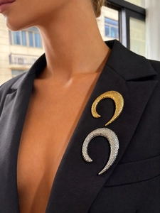 Detail of gold and silver U-shaped textured brooches pinned on a black suit lapel