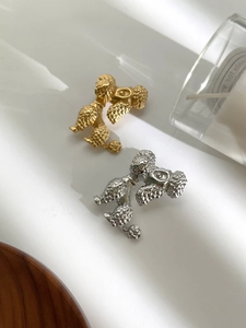 Macro detail of poodle-shaped metal brooches in gold and silver with textured fur detail