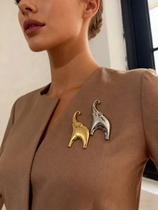 Detailed close-up of golden and silver elephant brooches on a brown suit lapel