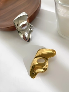 Macro detail of polished gold and silver mask pendants with artistic mirror finish