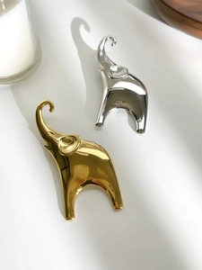 Detailed view of polished gold and silver elephant brooches with reflective mirror finish