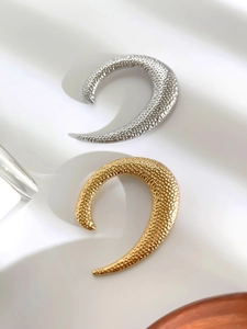 Detail of gold and silver hammered metal U-shaped pins with textured crescent surface