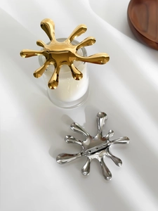 Macro shot of stylish gold and silver splash-shaped brooches with secure pin back design