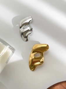 Macro shot of gold and silver mask brooches with a polished mirror finish surface