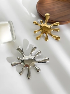 Close-up of modern gold and silver fireworks brooches on a rustic wooden tray