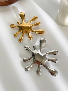 Detailed view of modern liquid splash brooches in polished gold and chrome finishes