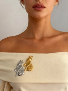 Détail d'une broche chat vintage en or et argent sur un vêtement beige élégant