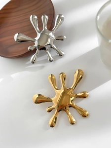 Macro shot of liquid splash shaped stainless steel brooches in gold and silver finish