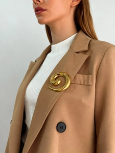 Detail shot of a golden spiral stainless steel brooch pinned on a blazer lapel