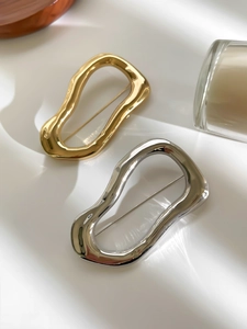 Detail of minimalist irregular geometric brooches in polished gold and silver finish
