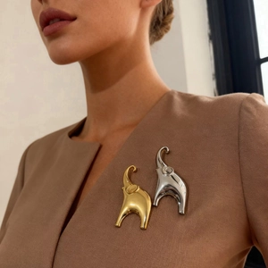 Elegant gold and silver elephant brooches styled on a brown blazer lapel for women