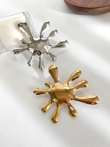 Macro detail of high-polish liquid metal fireworks brooches in gold and silver on silk