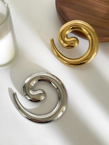 Detailed view of twisted snail-shaped brooches in polished gold and silver finishes