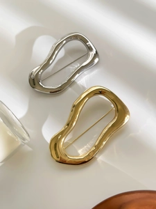 Detailed macro view of minimalist irregular gold and silver organic shape metal brooches
