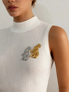 Détail de broches en forme de chat or et argent sur un tissu en maille blanche
