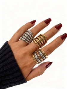 Close-up of wide multi-layer stacked rings in gold and silver finish on a female hand