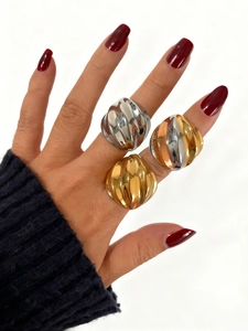 Primer plano de tres anillos gruesos con textura de ondas en acabado oro y plata