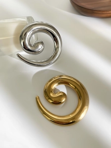 Detailed view of snail twist metal brooches in high-polished gold and silver finishes