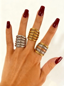 Close-up of three layered wavy texture rings in gold, silver, and tricolor finishes