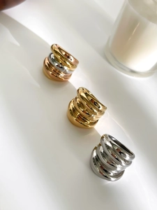Detailansicht der mehrlagigen, welligen Ringe in Gold, Silber und Roségold