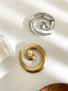Detail view of twisted gold and silver snail brooches with polished mirror finish